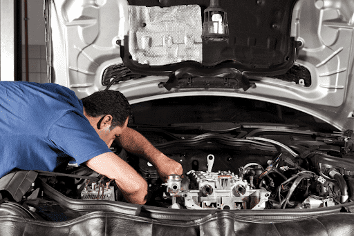 Trustworthy auto repair shop in Killeen, TX with First Choice Automotive. Image of mechanic leaned over car with hood open in the shop performing auto repair on the engine.