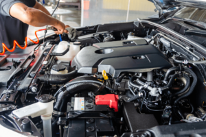 Stay Ahead of Cold Weather Threats with a Pre-Winter Engine Check in Killeen, TX with. First Choice Automotive. Image. of mechanic using tool to check all components under the hood of car. to get it ready. for winter.